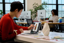 Donna utilizza il touchscreen del nuovo MacBook Pro 2026 di Apple durante un lavoro di progettazione grafica