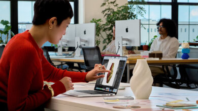 Donna utilizza il touchscreen del nuovo MacBook Pro 2026 di Apple durante un lavoro di progettazione grafica