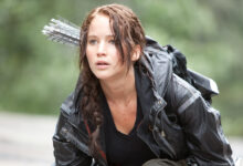 Jennifer Lawrence nei panni di Katniss Everdeen in Hunger Games, con arco e frecce sulla schiena.
