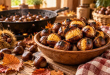 Castagne arrosto appena cotte in una ciotola rustica, con castagne fresche e foglie autunnali